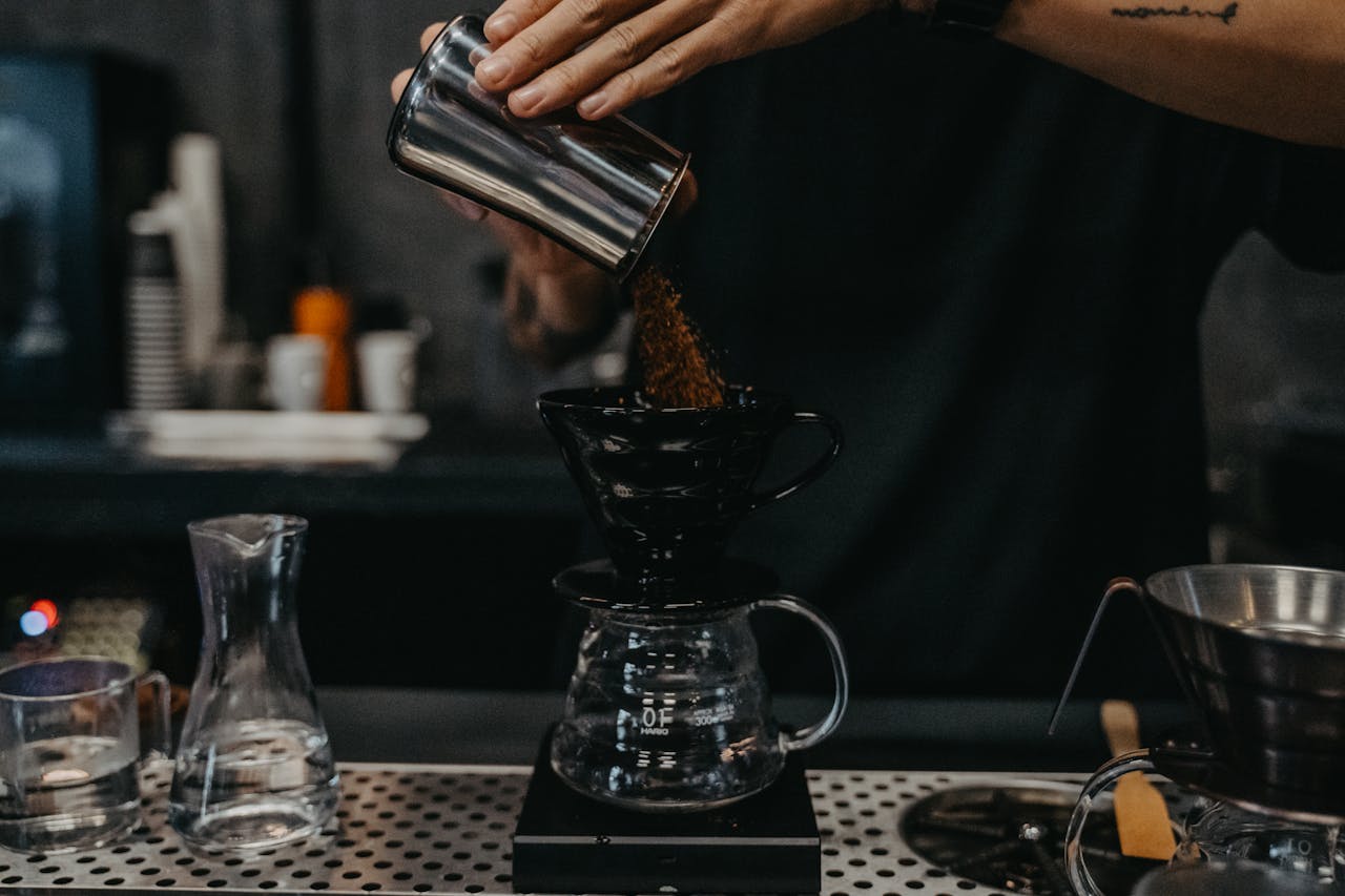 Close-up of a barista making pour-over coffee in a cafe with precise technique.